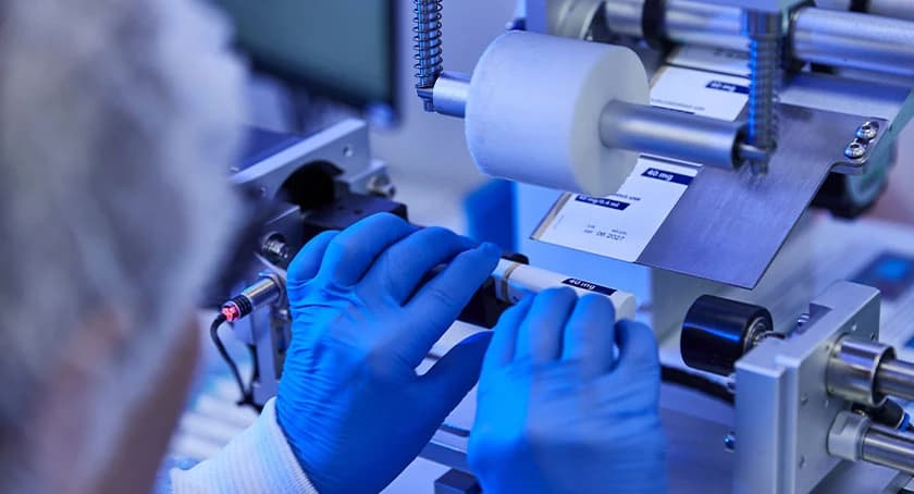 Gloved hands assembling a drug delivery device in a laboratory