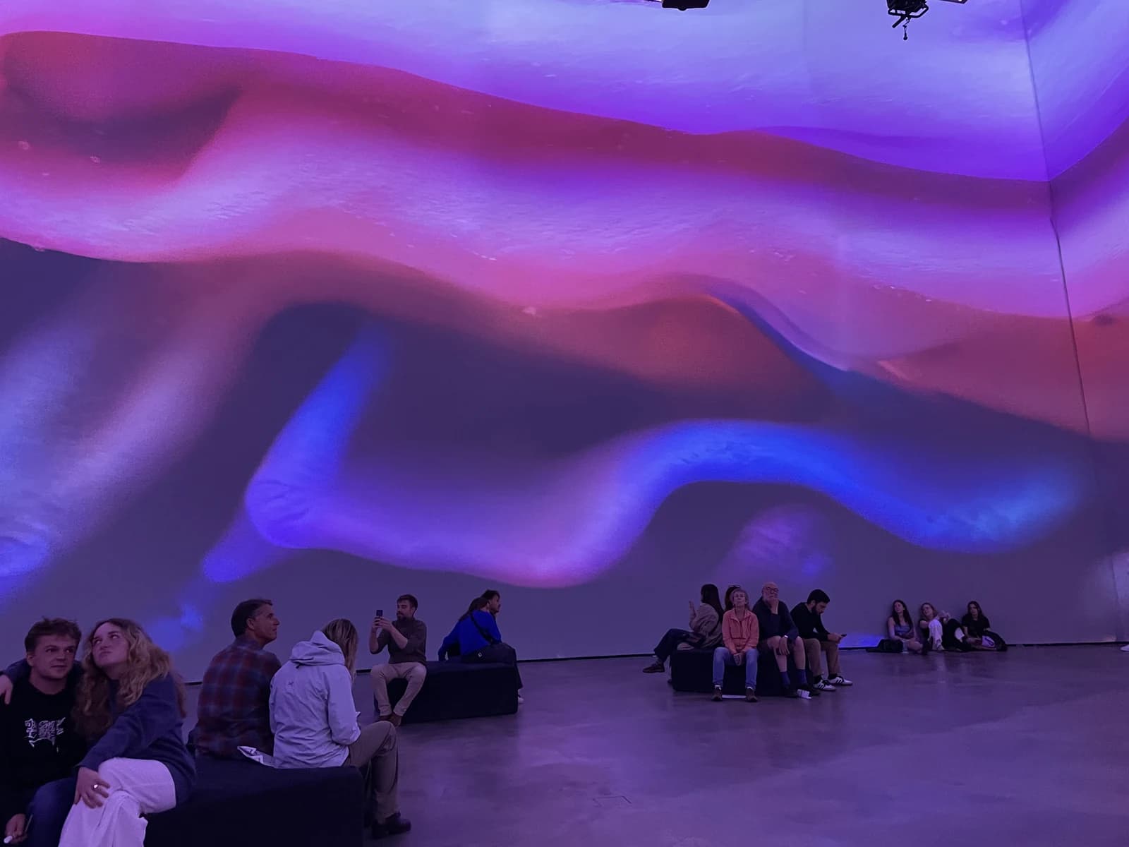 Visitors sitting inside a large immersive light installation